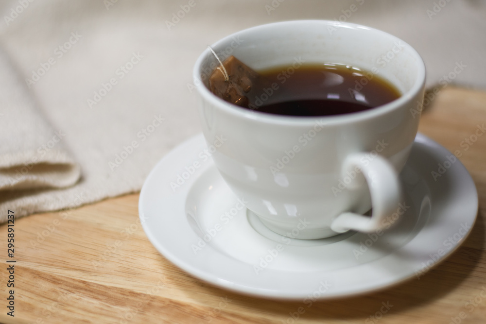 Cup of tea with tea bag dipping in hot water on wooden and cotton fabric background. Cup of tea with tea bag dipping in hot water on wooden and cotton fabric background.