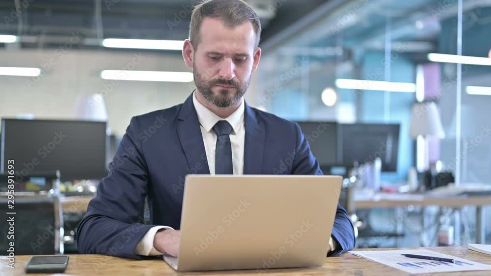 Young Businessman working on Laptop on Office Desk Young Businessman working on Laptop on Office Desk