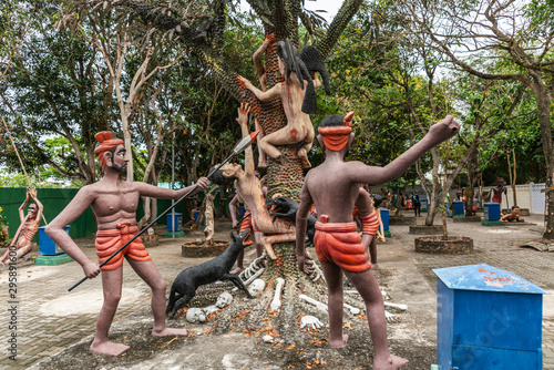 Bang Saen, Thailand - March 16, 2019: Garden of Hell in Wang Saensuk Buddhist Monastery. Scene wherein devils chase adulterous couple up a tree where wolves and black bird bite them. photo