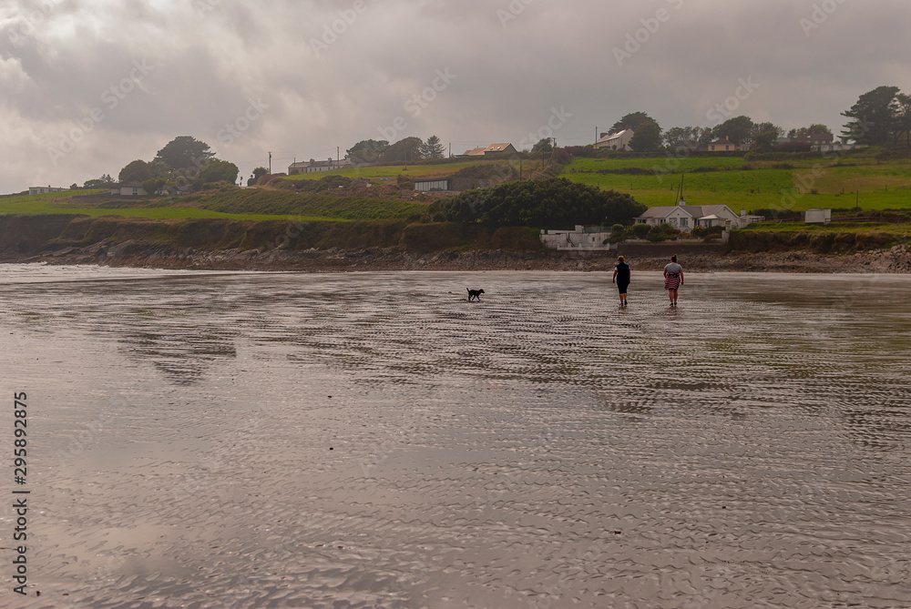 One man and a woman walking on sandy beach. One father and his daughter enjoying the day. family. One man and a woman walking on sandy beach. One father and his daughter enjoying the day. family.