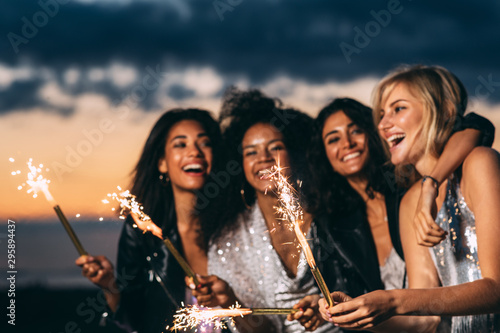 Close up of happy women holding sparklers at sunset