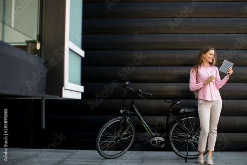 Young woman with tablet and e-bike outdoor