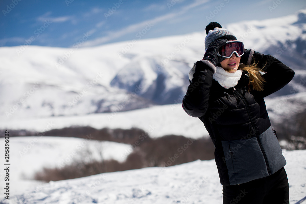 Young woman stands on a snowy  mountain slope in her ski suit
