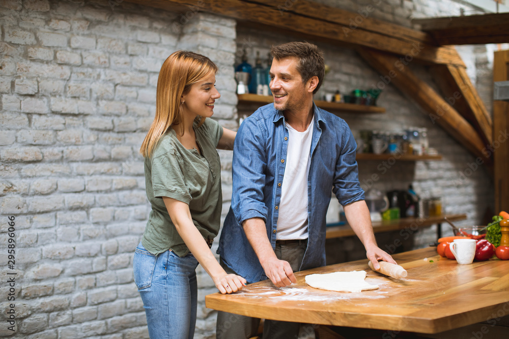 Young couple making pizza in rustic kitchen together Young couple making pizza in rustic kitchen together