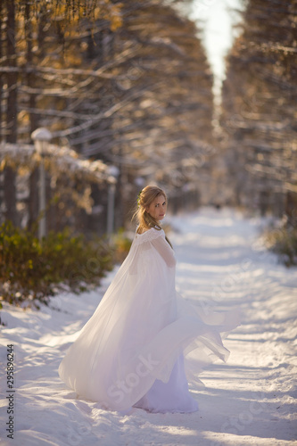  beautiful girl in a white dress walks in the winter forest