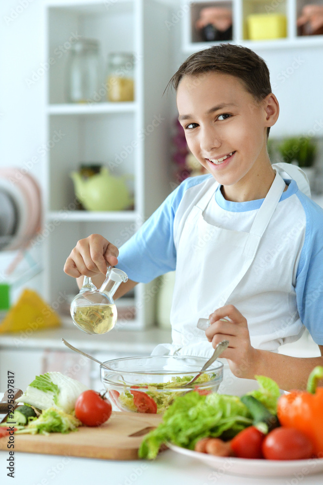 Portrait of boy preparing salad on kitchen table at home