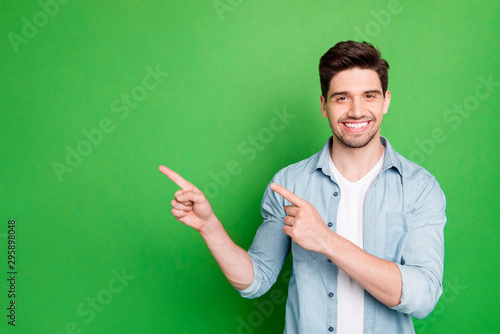 Photo of amazing salesman guy in excited mood indicating finger to empty space advising cool shopping prices wear casual denim shirt isolated green color background photo