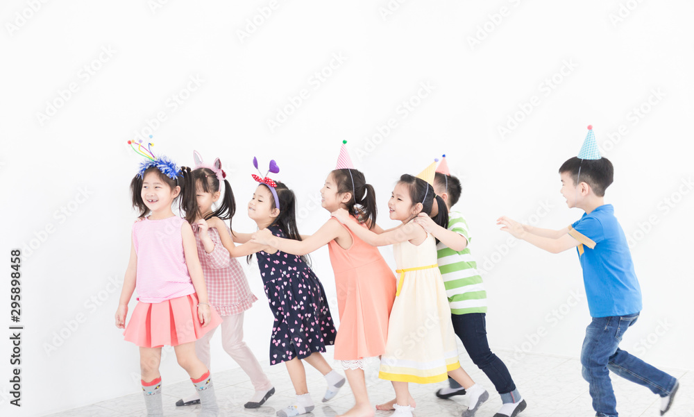 Obraz premium pretty asian children group holding hand on friends shoulder and walk on gray background, they feeling happy in birthday party, they smile and play together, recreation activity