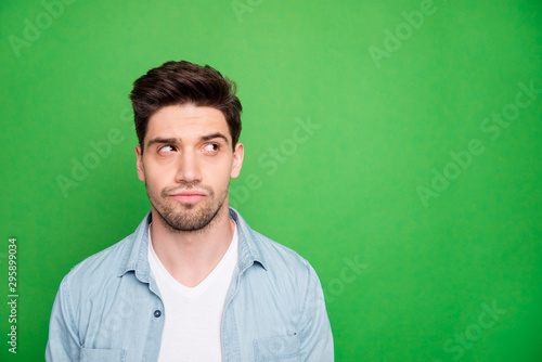 Photo of attractive bristled bearded man looking into empty space trying to find necessary information there isolated over green vivid color background