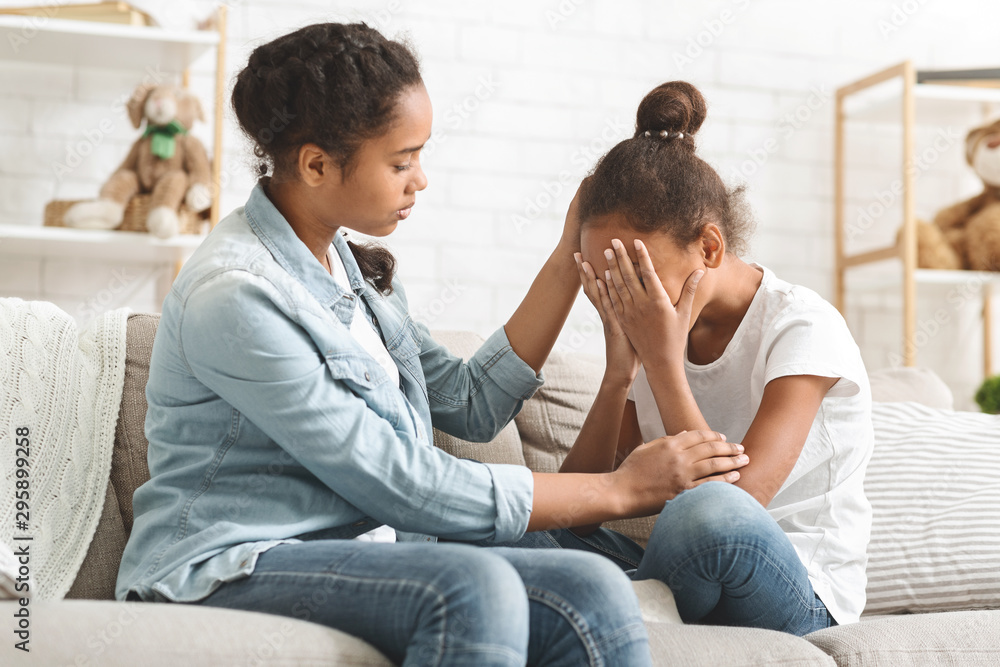 Crying little girl being consoled by her elder sister Crying little girl being consoled by her elder sister