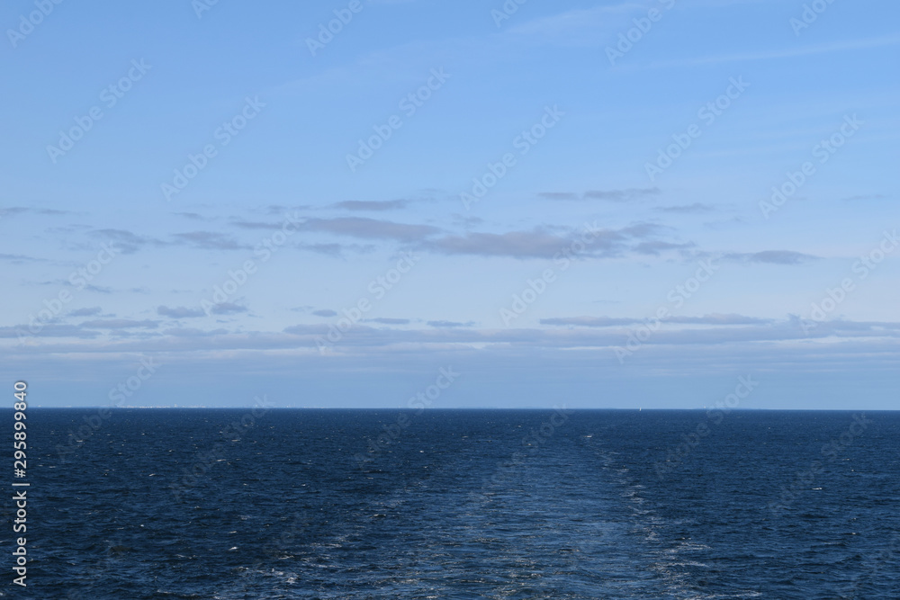 Deep blue sea with trail on water surface behind of moving cruise ship and endless skyline Deep blue sea with trail on water surface behind of moving cruise ship and endless skyline