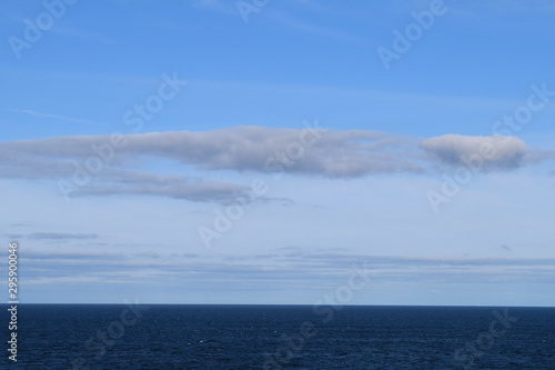 Dark blue sea with smooth water surface behind of moving cruise ship and endless skyline