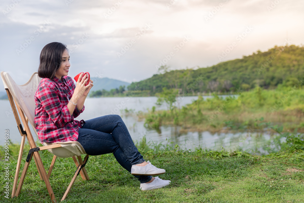 smart asian female travel in forest, she holding red ceramic cup and drinking hot coffee at lakeside , she sitting on seat, adventure activity and travel smart asian female travel in forest, she holding red ceramic cup and drinking hot coffee at lakeside , she sitting on seat, adventure activity and travel