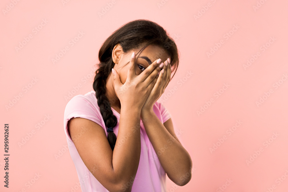 Teen girl peeping at the camera through her fingers Teen girl peeping at the camera through her fingers