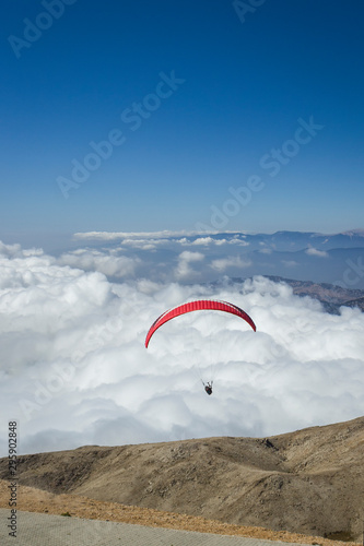 Paraglider silhouett against a cloudy blue sky.