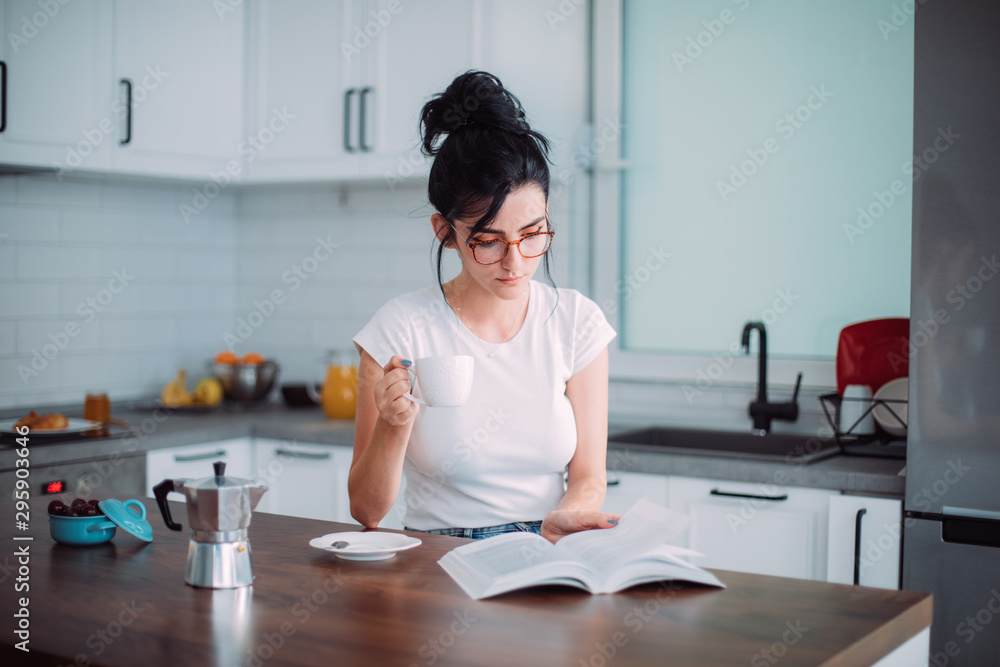 Beautiful young woman reading book in the kitchen Beautiful young woman reading book in the kitchen
