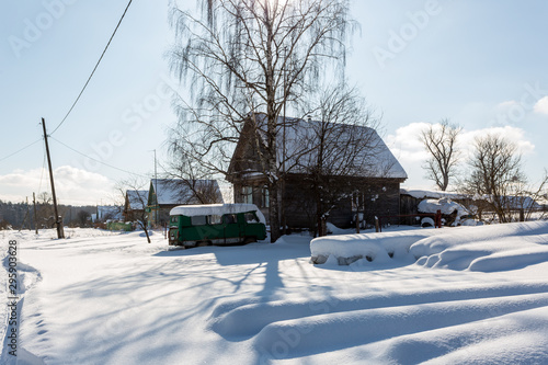 Early winter morning. Street in traditional Russian village in snowy frost winter