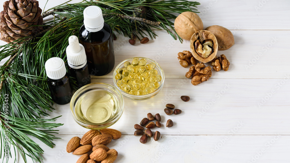 top view natural essential oils of cedar, almond, walnut, on a wok of cedar branches on a light wooden table. top view natural essential oils of cedar, almond, walnut, on a wok of cedar branches on a light wooden table.