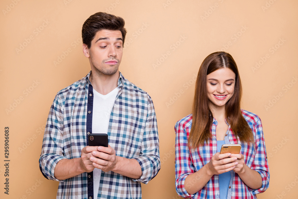Hmm interesting.... Portrait of pensive guy use his smartphone watch who secret admirer his wife chatting on social network account wear checkered shirt isolated over beige color background Hmm interesting.... Portrait of pensive guy use his smartphone watch who secret admirer his wife chatting on social network account wear checkered shirt isolated over beige color background