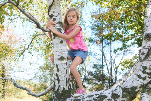 Child brave cute girl climbing on tree