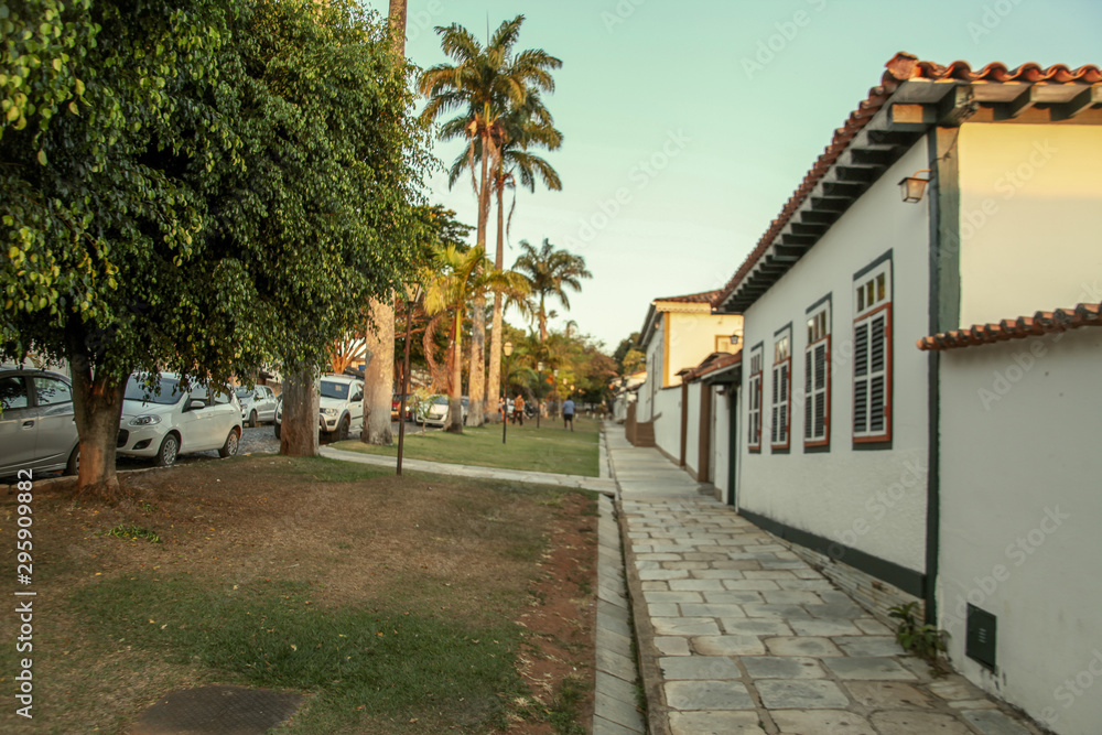 Pirenopolis, Goias, Brazil, October 18, 2019: The facades of colonial-style houses with natural stone sidewalks in the late afternoon on the tree-lined streets in the historic center of Pirenopolis