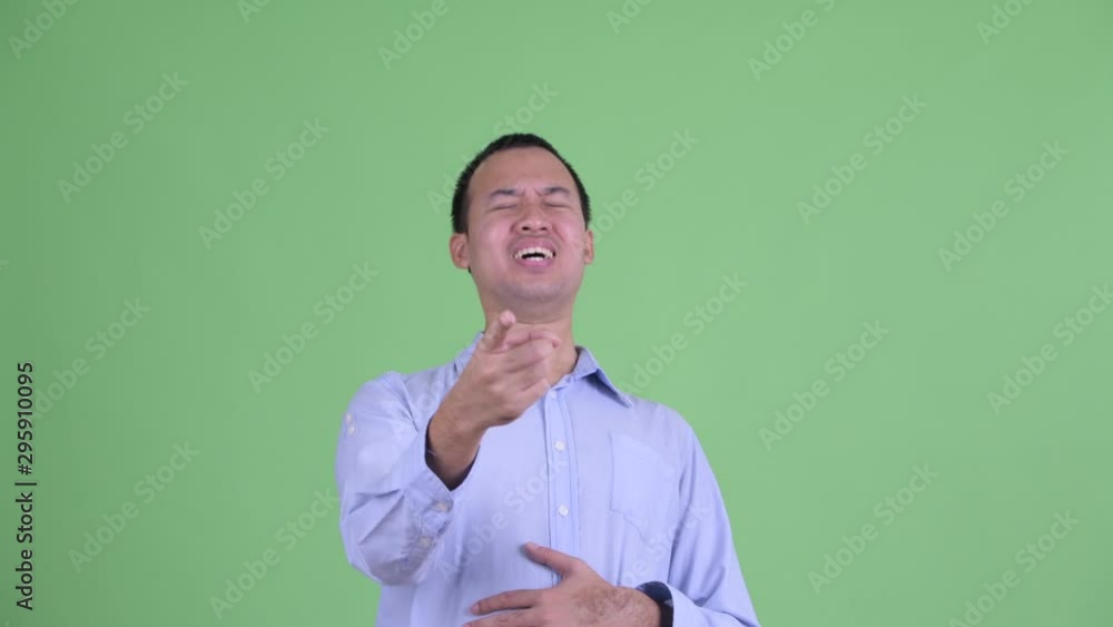 Studio shot of happy Asian businessman laughing and pointing at camera Studio shot of happy Asian businessman laughing and pointing at camera
