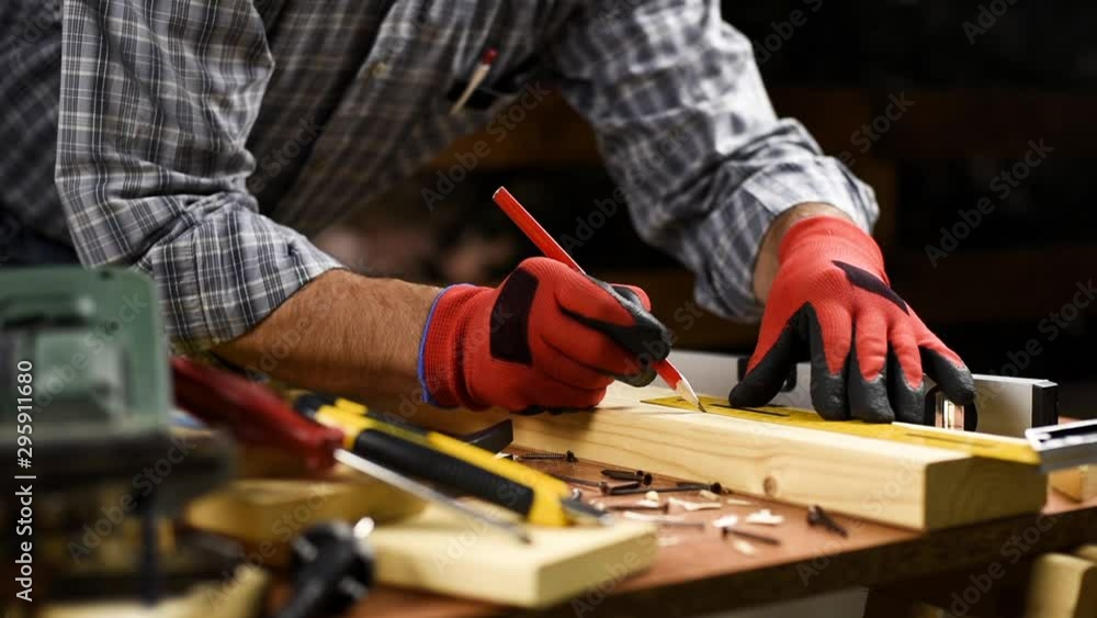 Adult carpenter craftsman wears protective gloves, with a pencil and the carpenter's square trace the cutting line on a wooden table. Construction industry, housework do it yourself. Footage. Adult carpenter craftsman wears protective gloves, with a pencil and the carpenter's square trace the cutting line on a wooden table. Construction industry, housework do it yourself. Footage.