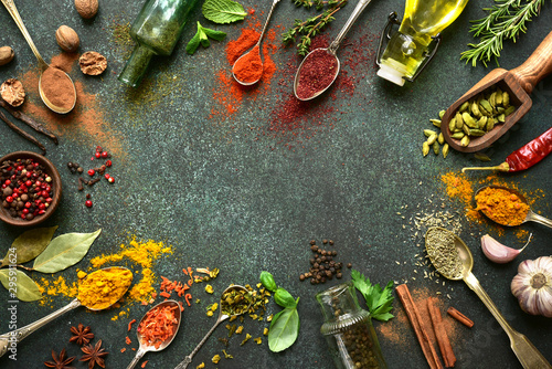 Variety of natural organic spices on a spoons on a dark green slate, stone or concrete background. Top view with copy space.