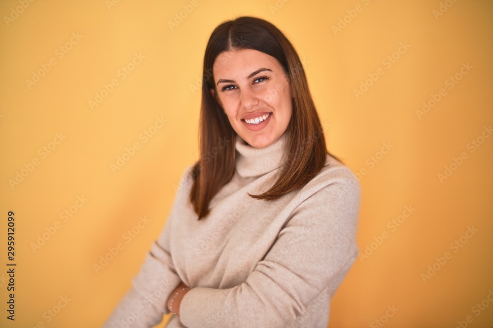 Obraz premium Young beautiful woman smiling happy wearing a sweater over isolated yellow background