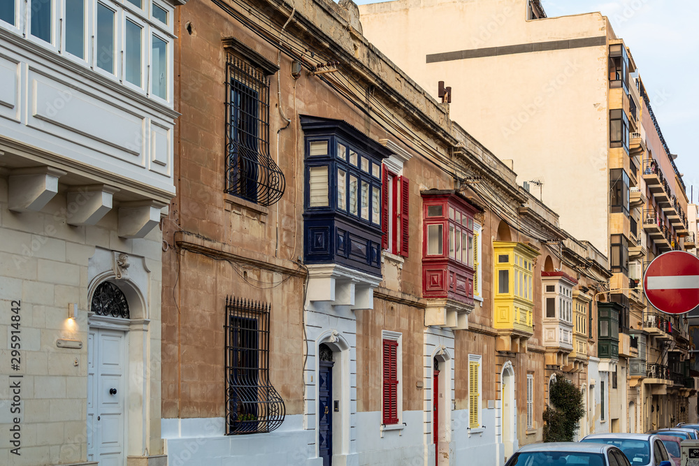 Residential house facade with traditional Maltese multicolored wooden balconies in Sliema, Malta, in evening sunlight. Authentic Maltese urban scene.