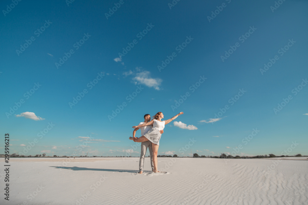 Romantic couple dancing in sand desert at blue sky background. Romantic couple dancing in sand desert at blue sky background.