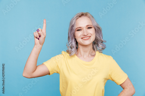 Portrait of happy female showong by finger up in the blue studio photo