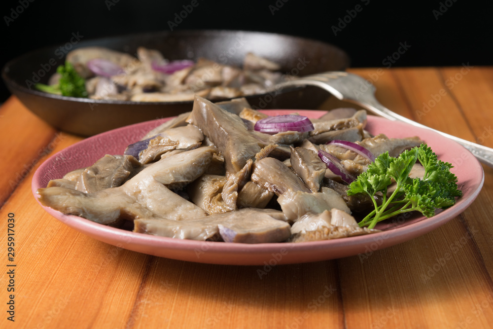 Fried mushrooms on a lilac plate stands on a beautiful wooden background Fried mushrooms on a lilac plate stands on a beautiful wooden background