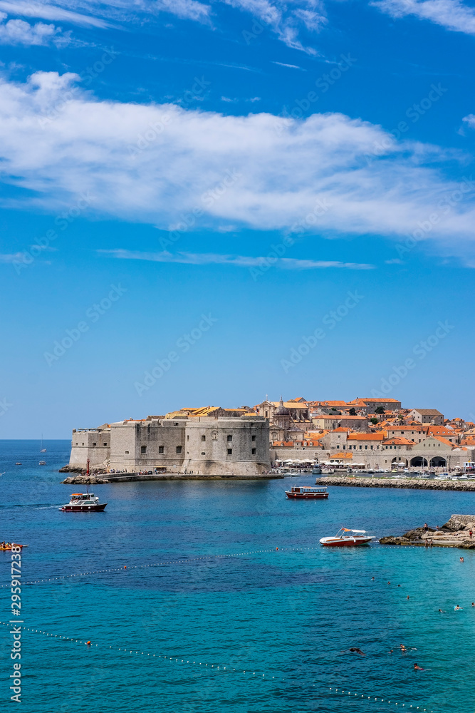 Old city walls in historic Dubrovnik city, Dalmatia, Croatia, emerald Adriatic Sea and blue summer sky with clouds, popular touristic destination, nice background image