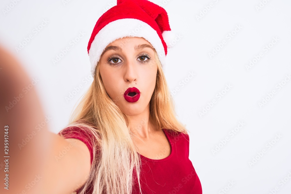Woman wearing Christmas Santa hat make selfie by camera over isolated white background scared in shock with a surprise face, afraid and excited with fear expression Woman wearing Christmas Santa hat make selfie by camera over isolated white background scared in shock with a surprise face, afraid and excited with fear expression