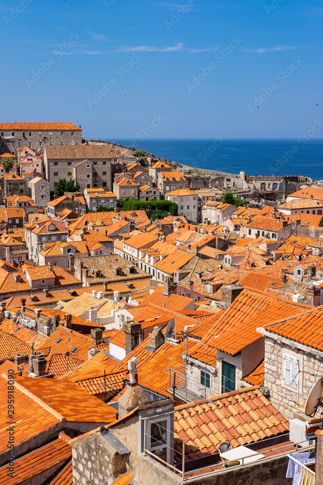 Old stone houses with red roofs in old historic Dubrovnik city, stone city walls in background on sunny summer day, Dalmatia, Croatia, the most popular touristic destination