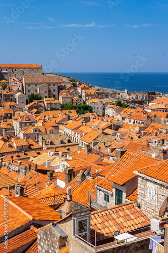Old stone houses with red roofs in old historic Dubrovnik city, stone city walls in background on sunny summer day, Dalmatia, Croatia, the most popular touristic destination