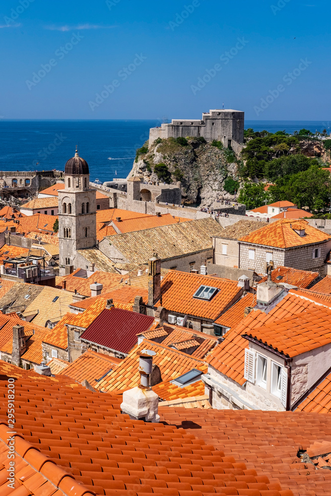 View on the Fort Lovrijenac from old city walls, Dubrovnik, Dalmatia, Croatia, with red houses roofs, blue sky and blue Adriatic Sea. The tourist destination is known for the show Game of Thrones