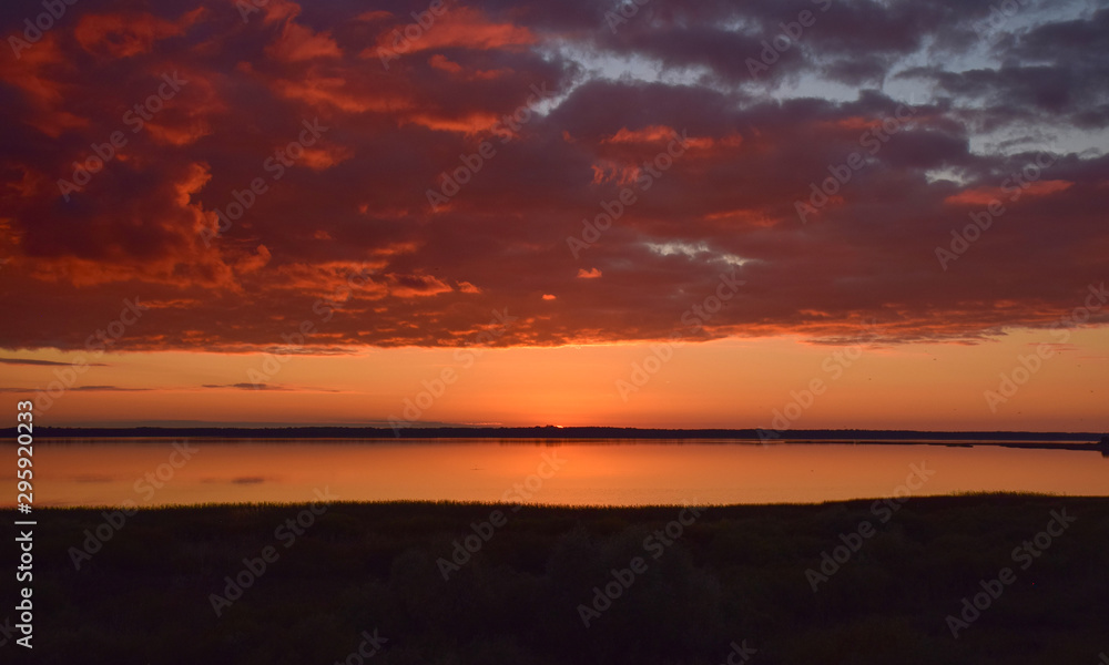 Beautiful serene colored sunset over Burtnieku lake  and lake reflections of the sky above, Latvia 