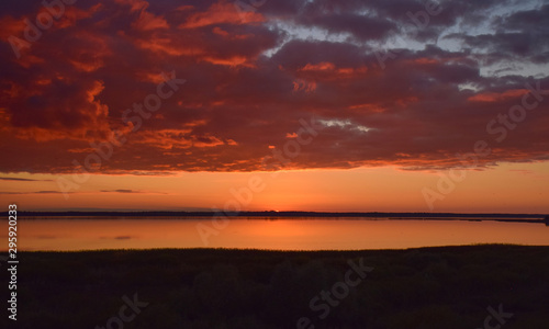Beautiful serene colored sunset over Burtnieku lake and lake reflections of the sky above, Latvia 