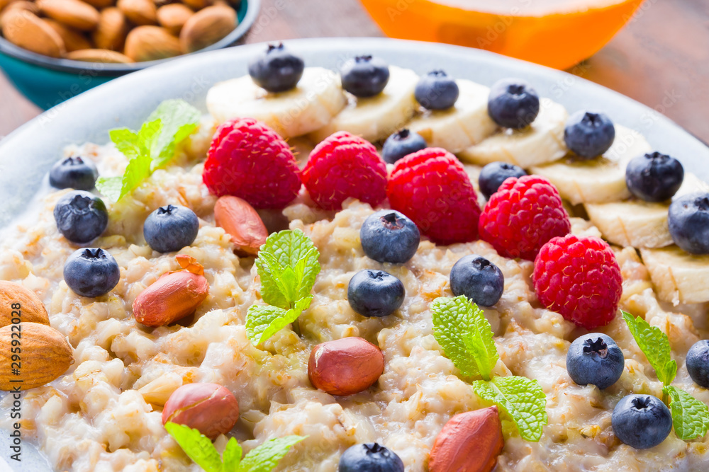 Bowl of oatmeal porridge with berries, honey and fruits on burlap. Tasty oatmeal with raspberries, blueberries and nuts on wooden boards. Healthy breakfast Bowl of oatmeal porridge with berries, honey and fruits on burlap. Tasty oatmeal with raspberries, blueberries and nuts on wooden boards. Healthy breakfast