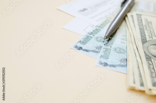 1040 Individual Income tax return form with Refund Check and hundred dollar bills on beige background photo