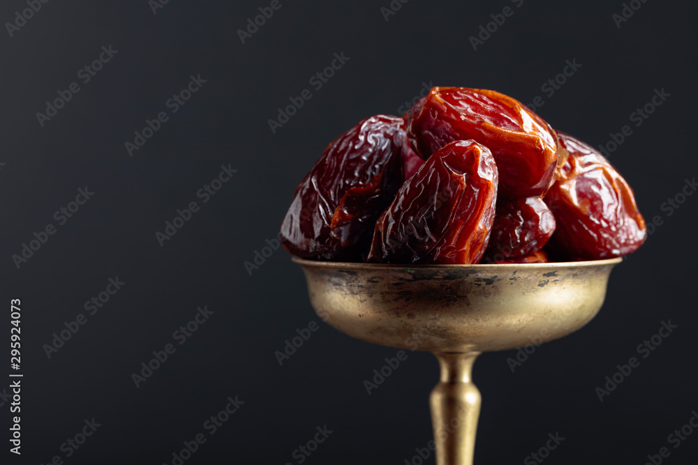 Closeup sweet dried dates in brass dish. - obrazy, fototapety, plakaty 