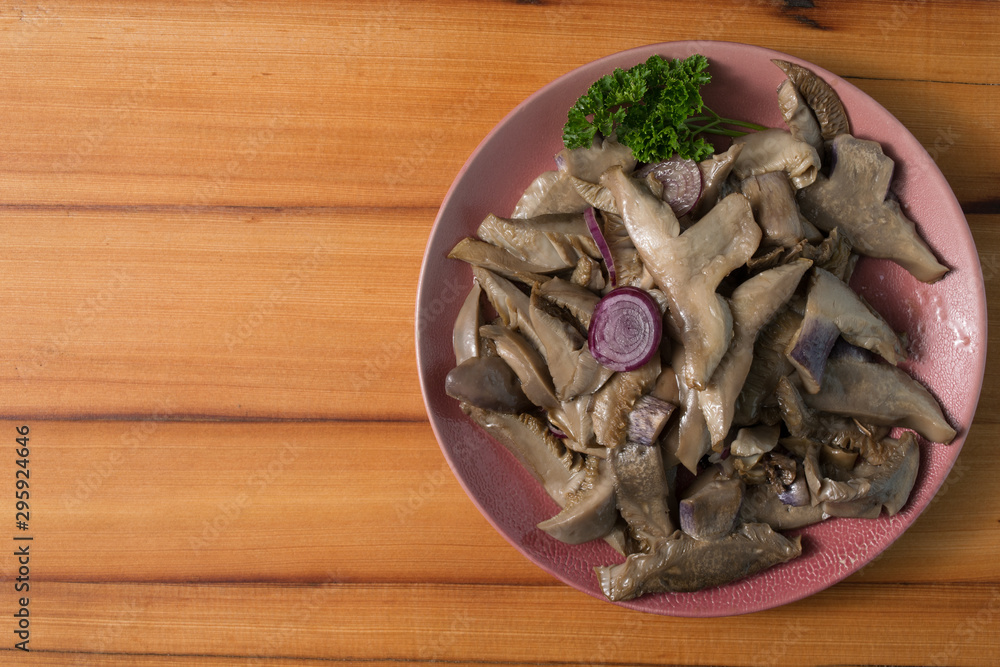 Fried mushrooms on a lilac plate stands on a beautiful wooden background Fried mushrooms on a lilac plate stands on a beautiful wooden background