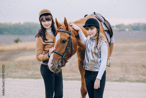 First lessons of horseback riding. Mom and daughter learn to ride a horse.  