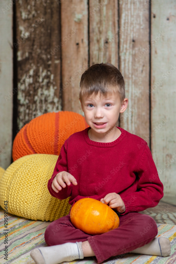 Fototapeta premium a boy in a red sweater with a orange pumpkin