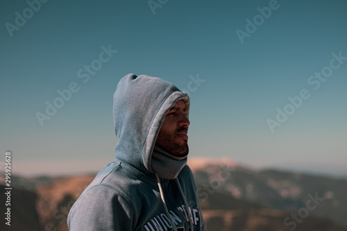 Joven con capucha azul en la naturaleza rodeado de montañas