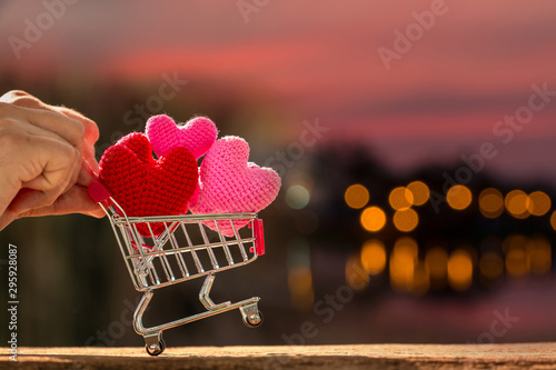 Foto Man pushing a shopping cart and the heart put on inside put on the wood on beautiful bokeh background, Buy insurance or for give supporting when people get who lack of desire with love concept