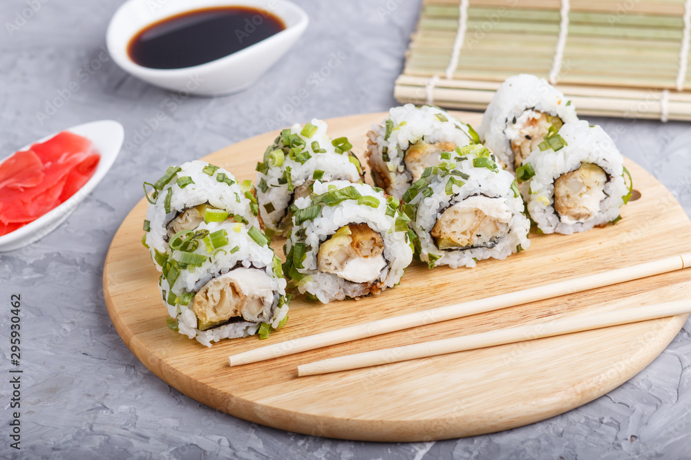 Japanese maki sushi rolls with green onion on wooden board on a gray concrete background. Side view Japanese maki sushi rolls with green onion on wooden board on a gray concrete background. Side view