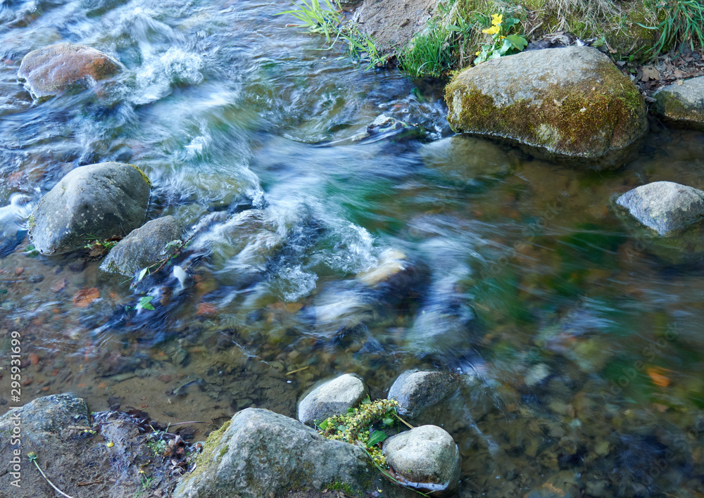 A stream of water in a stream flowing between stones